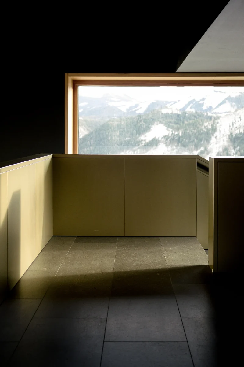 All'interno del Planetarium (BZ). Finestra con panorama montano e neve. Luce del sole proveniente dalla rampa di scale, con corrimano di design. Il resto della foto è scura e contrastata
